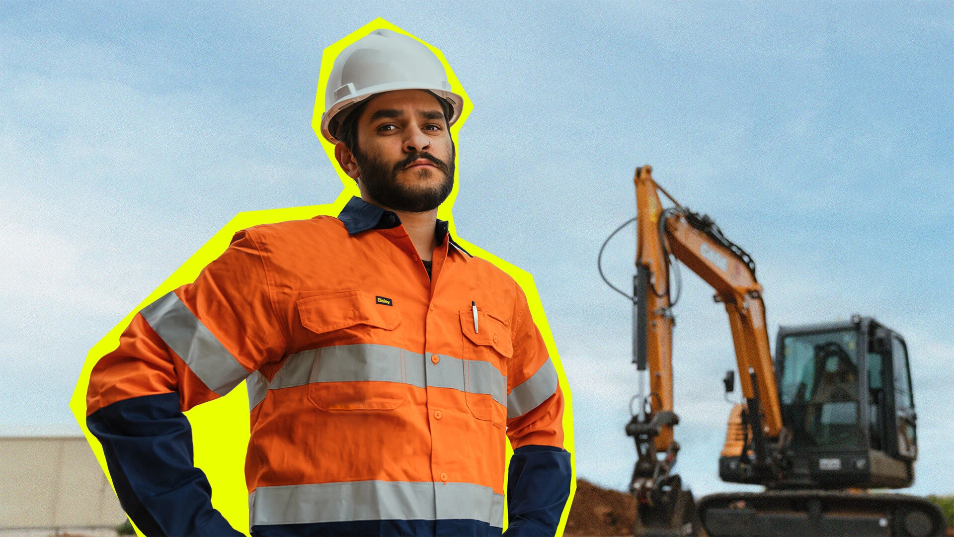 Tradie in Hi Vis standing in front of a large digger.